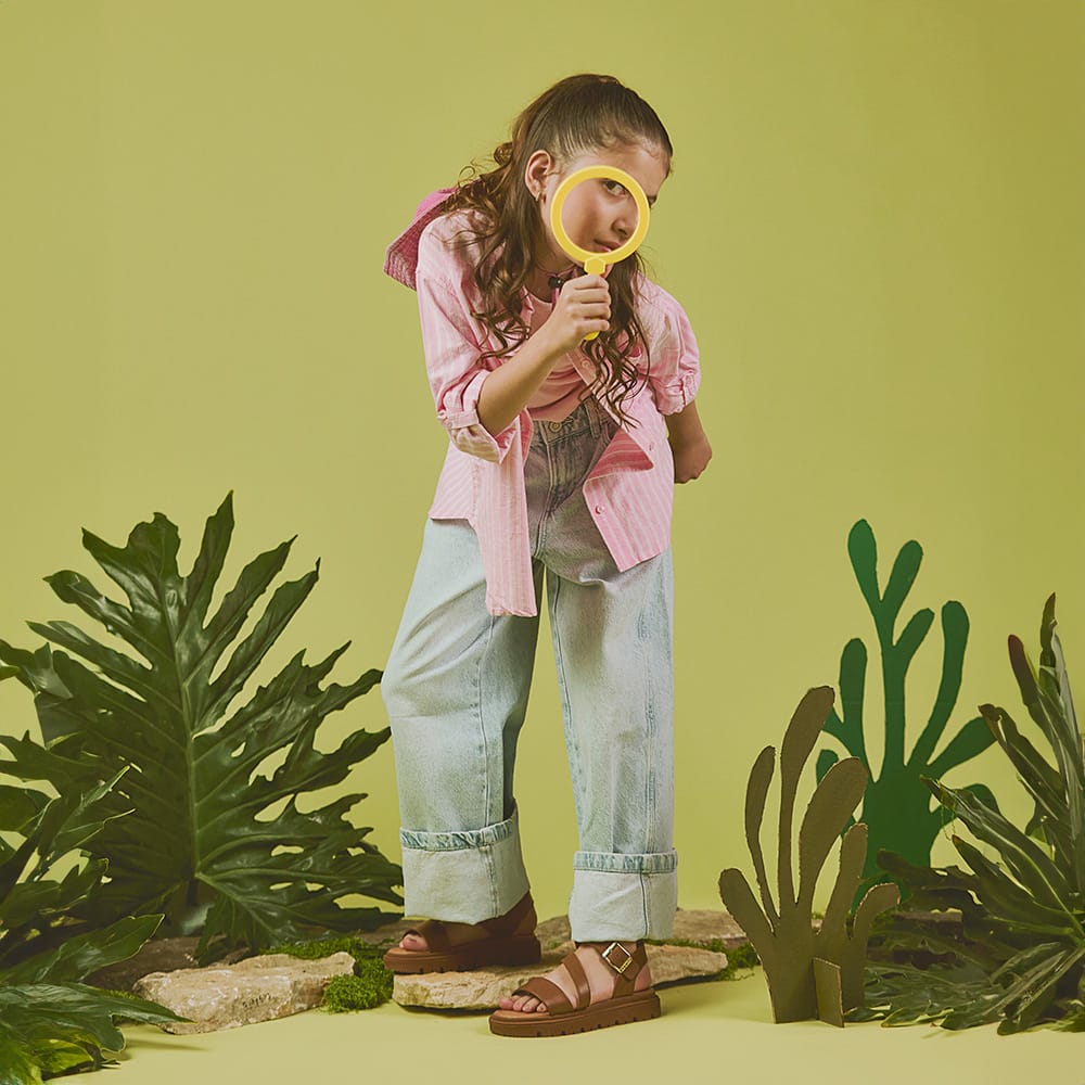 Niña usando sandalias infantiles Coqueta y Audaz color café con hebilla, calzado cómodo y resistente ideal para primavera verano y actividades al aire libre.